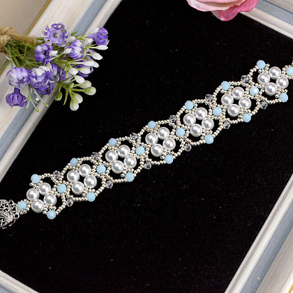 Браслет из кружева, украшенный синими стеклянными и жемчужными бусинами.